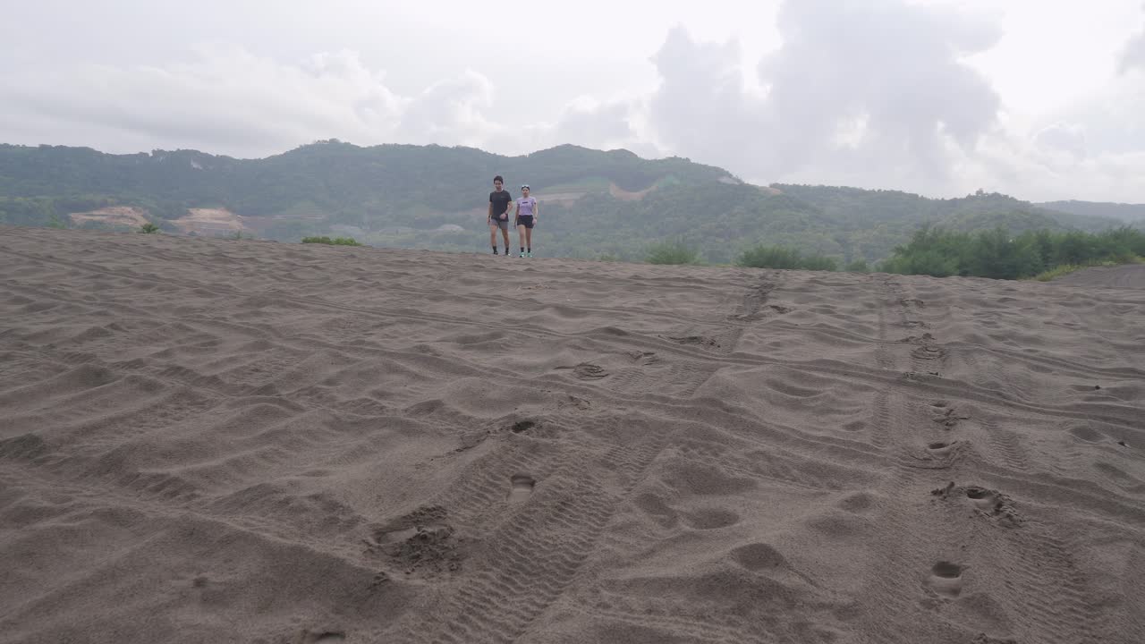 People Running on a Sand Dune