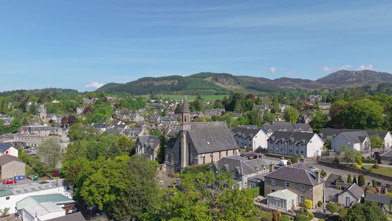 Orbiting the church of Pitlochry, Scotland, revealing the charming village, surrounding green hills, and scenic highland landscapes