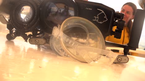 vintage oval diving mask and underwater camera housing with female diver in background