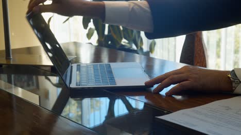 Nahaufnahme-Der-Hände-Eines-Geschäftsmannes,-Der-Einen-Laptop-In-Zeitlupe-Auf-Einem-Hölzernen-Schreibtisch-In-Einem-Büro-öffnet