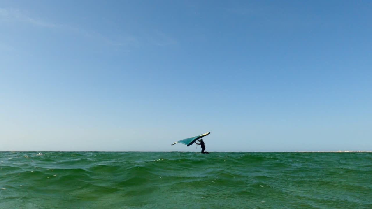 pov de ángulo bajo del hombre en kite board surfing en la superficie del mar