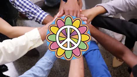 Peace symbol over mid section of diverse office colleagues staking their hands together at office