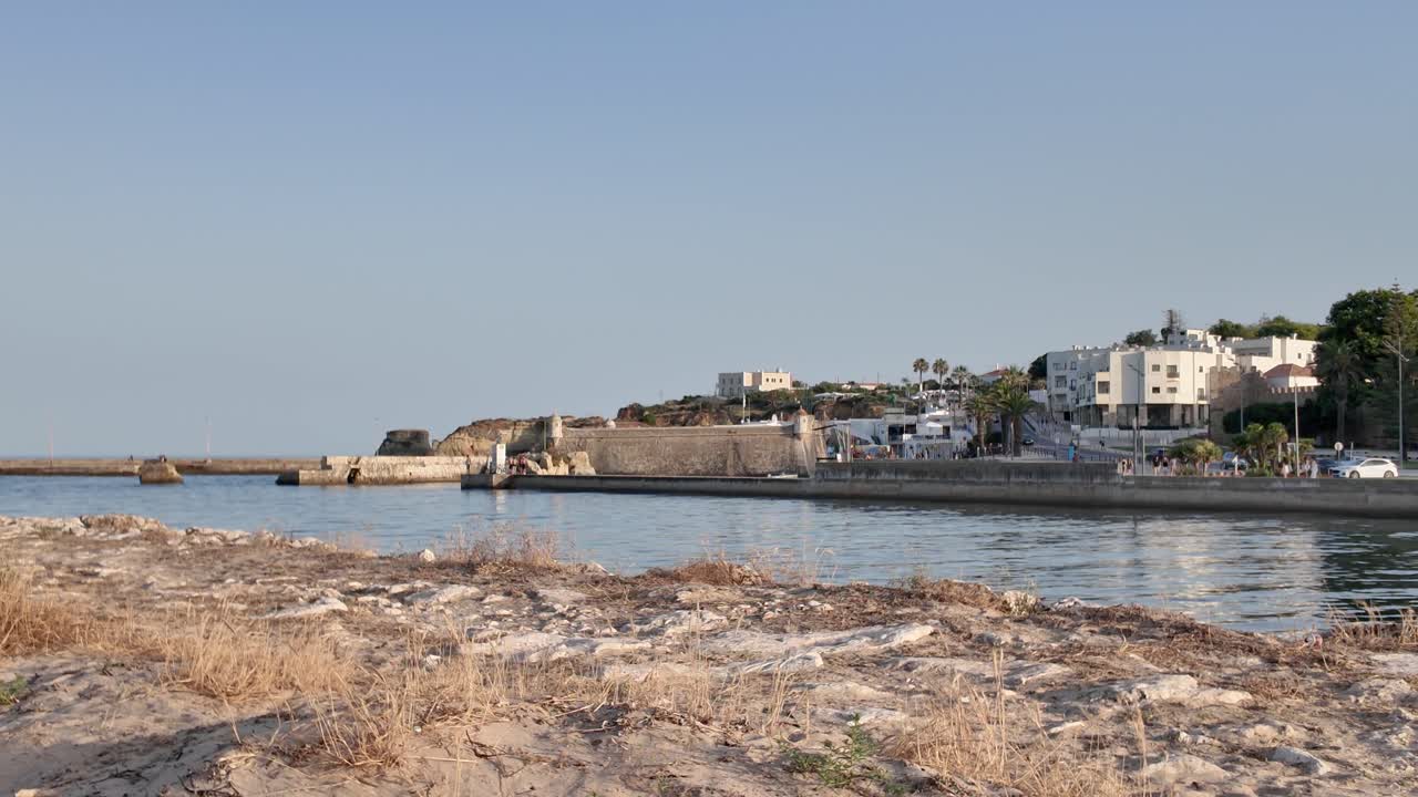 Coastal view of Lagos in Portugal with sandy foreground and distant buildings