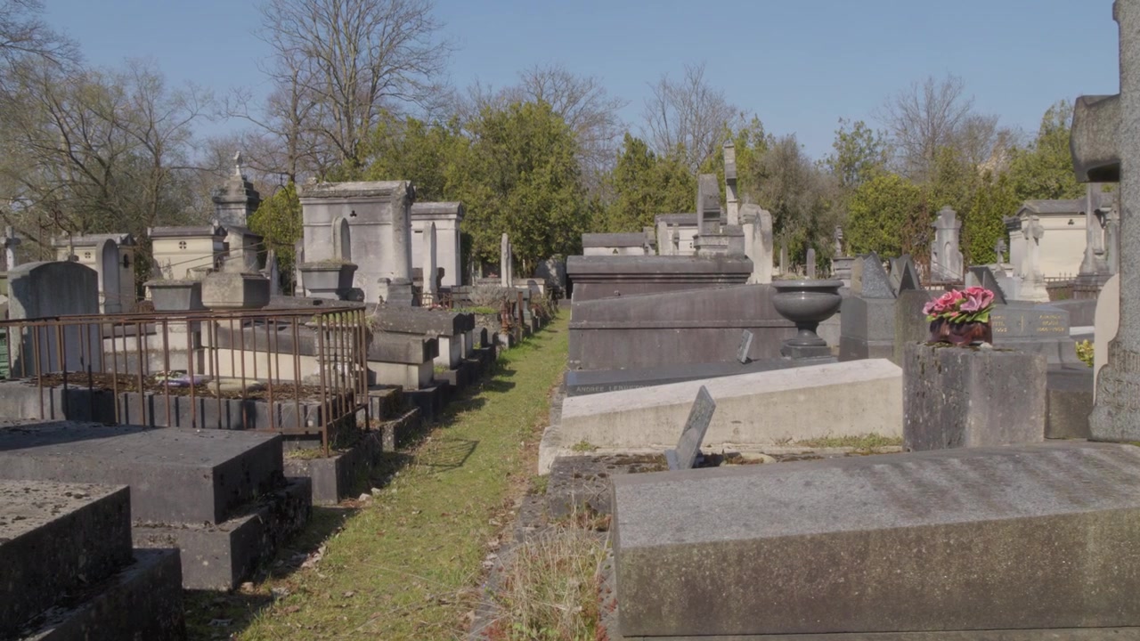 Vista panoramica su vecchie tombe, croci di pietra e mausolei al Cimitero di Père Lachaise a Parigi, con sentieri verdi, alberi spogli e un'atmosfera calma diurna.