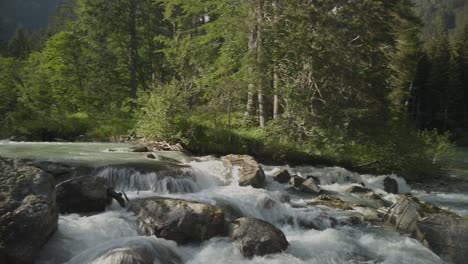 Kleine-Wasserfälle,-Die-Auf-Felsen-Mit-Wald-Im-Hintergrund-Fallen