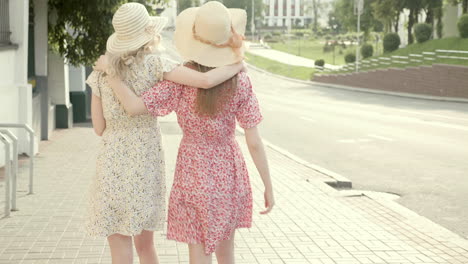 two women walking together in summer dresses and hats