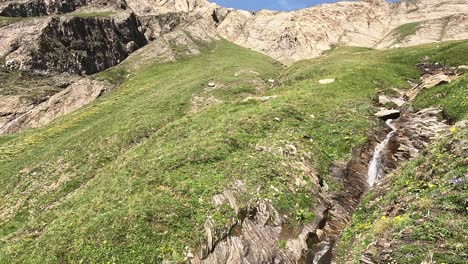 Blick-über-Einen-Wasserfall,-Der-Die-Steilen-Grashänge-Der-Italienischen-Alpen-Bei-Alpe-Bettelmann-Hinunterfließt