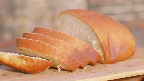 outdoors medium shot of freshly baked homemade white bread with slices on wooden chopping board. home baking footage with simple healthy ingredients outside 4k.