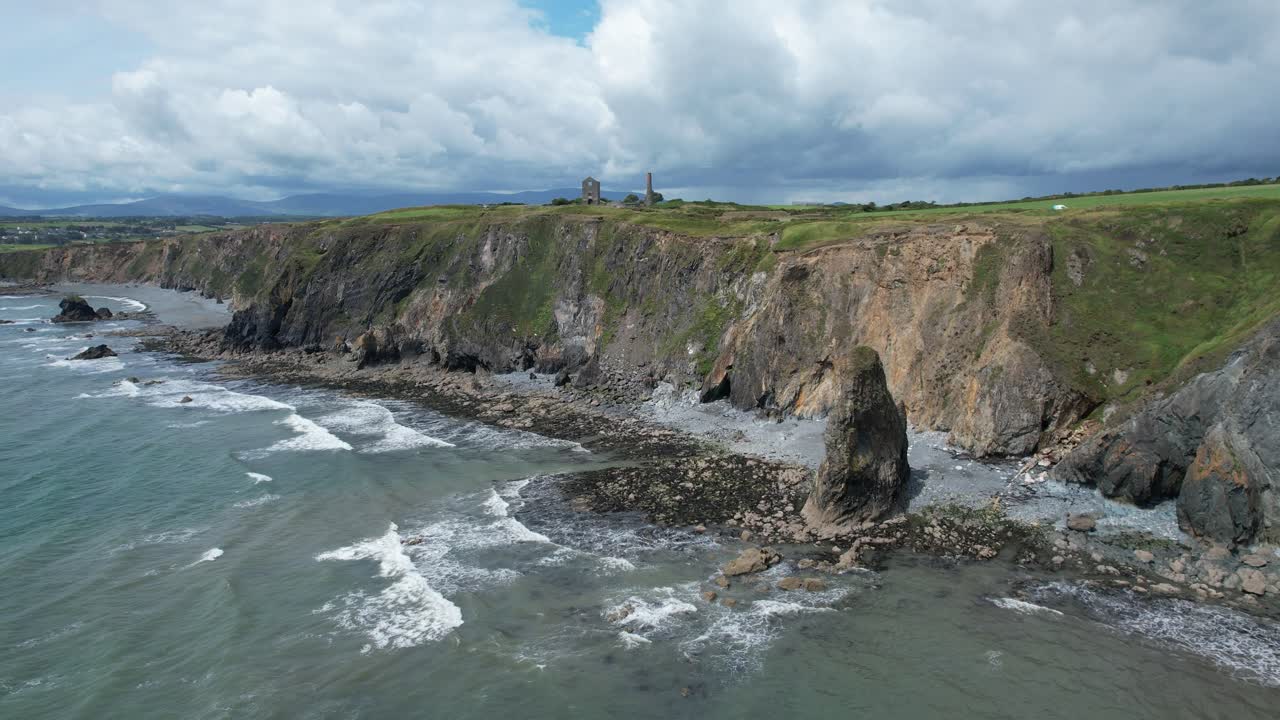 Incoming tide at Tankardstown Copper Coast Waterford Ireland with rain laden clouds approaching from the West Comeragh Mountains on a blustery summer day