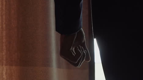 Silhouette-of-guy-in-office-suit-stands-near-window-in-hotel