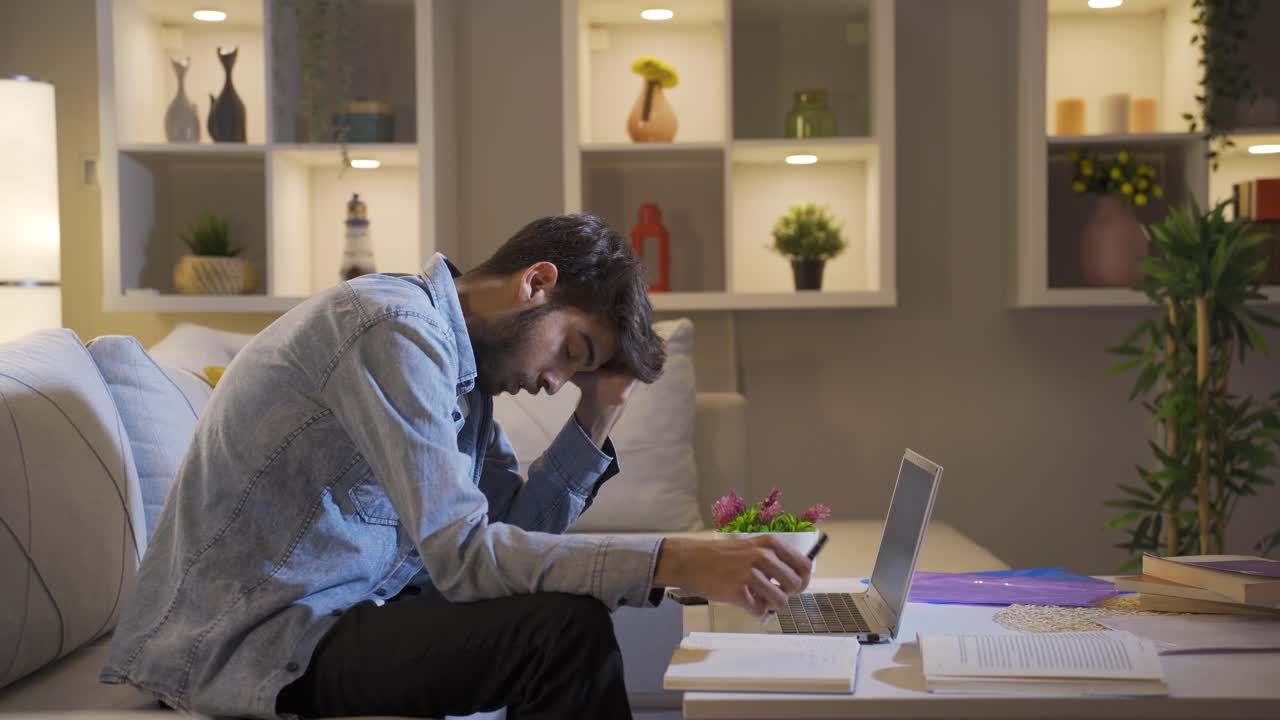 Man looking tired and exhausted at laptop at night.