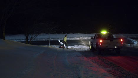 Plow-man-and-plow-truck-plowing-snow-on-road-at-night