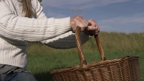 mujer recogiendo una cesta tejida retro en el campo tiro medio