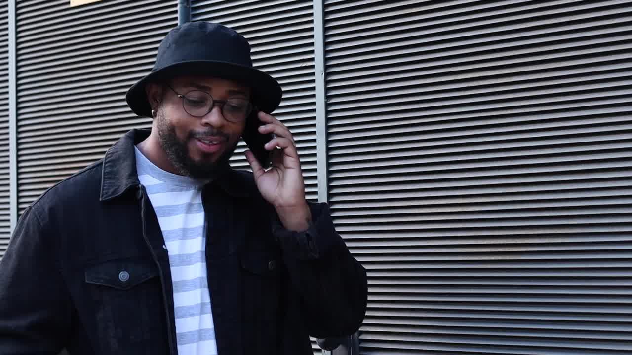 웃고 있는 흑인 남자가 스마트폰으로 이야기하고 있습니다.