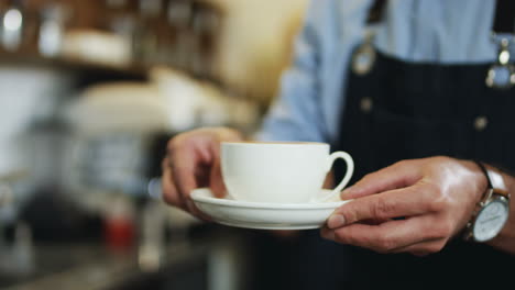 Close-Upof-The-Cup-Of-Coffee-Being-Given-From-Man's-Hands-Of-Barmen-To-The-Female-Client-At-The-Cafe