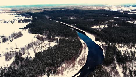 un río sinuoso cerca de un pequeño pueblo con un macizo forestal