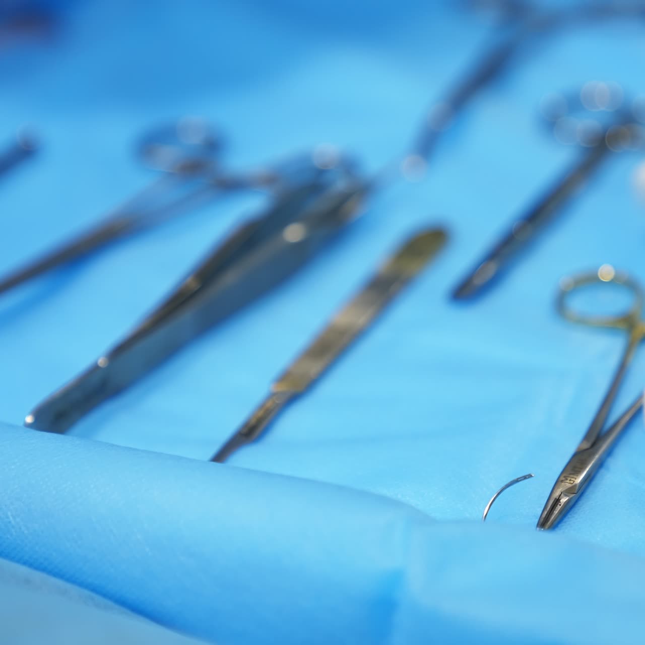 Metal instruments for surgical operation laid on the table. Cheesecloth sponges lie among the instruments. Close up