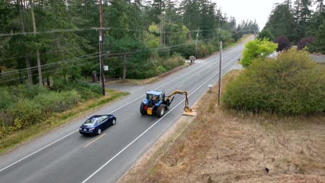 Drohnenaufnahme,-Die-Einem-Traktor-Mit-Einem-Mähaufsatz-Folgt,-Der-Dabei-Hilft,-Den-örtlichen-Straßenrand-Auf-Whidbey-Island-Zu-Reinigen