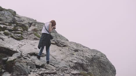 a young woman hiker climbs mountains with photo camera. transfagarasan, carpathian mountains in romania