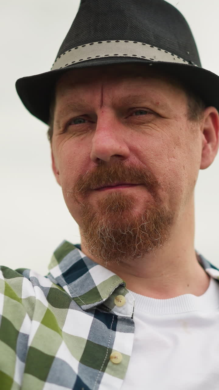 vista en primer plano de un artista con una camisa a cuadros y sombrero, sosteniendo un pincel con la mano borrosa, enfatizando su cara expresiva