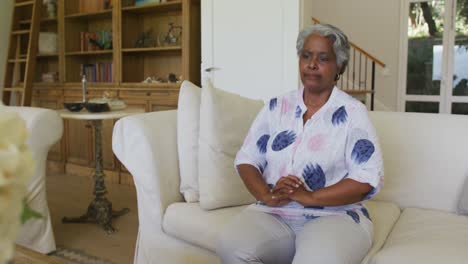 worried african american senior woman sitting on the couch at home