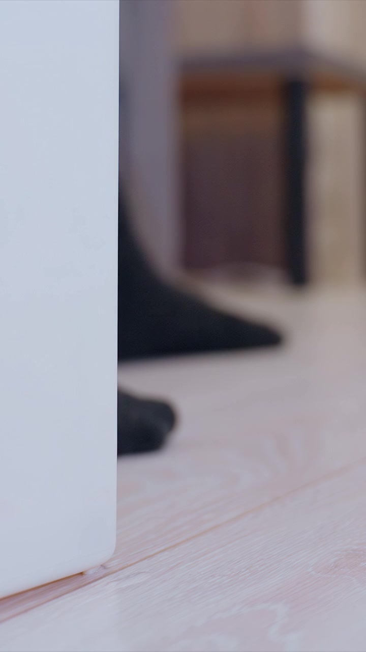 Close up shows base of modern household object positioned near furniture. scene is softly lit with shallow depth of field emphasizing texture and material details in indoor setting