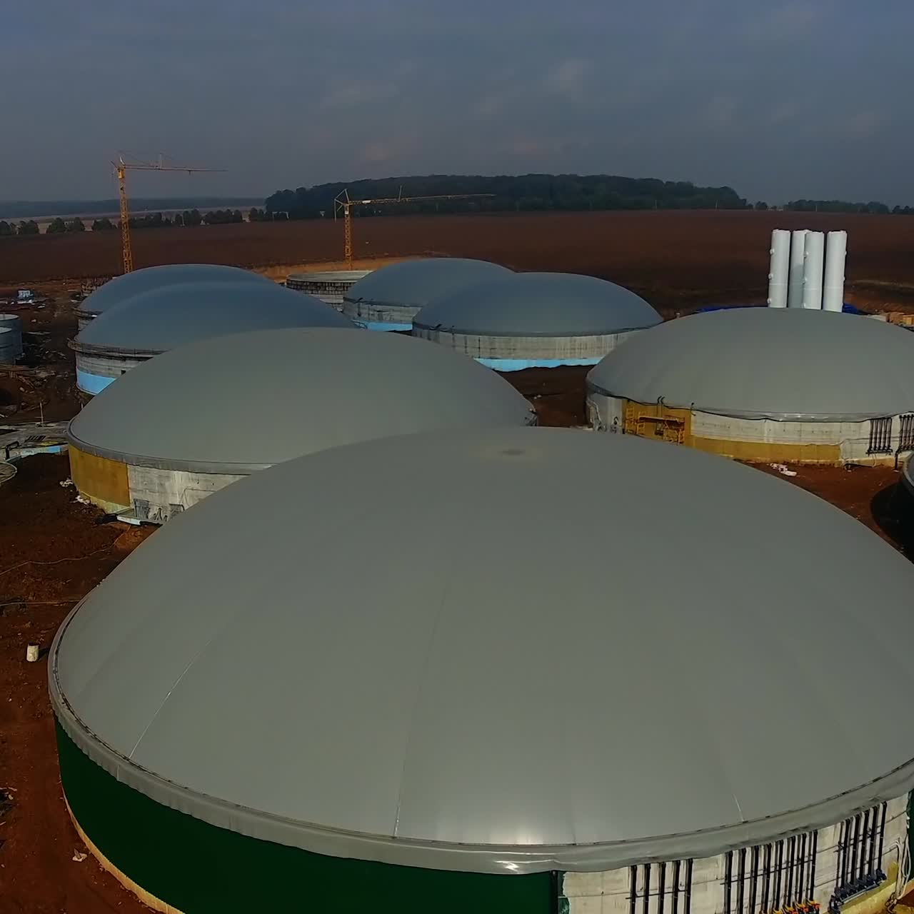 Building of bio gaz station in green field. Gray roofs and green walls of round metal construction