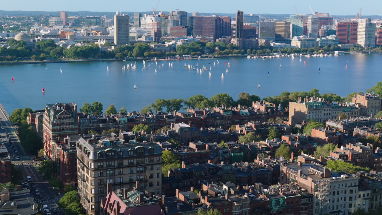 High angle shot of Charles River filled with sailboats and Boston skyline under sunny sky