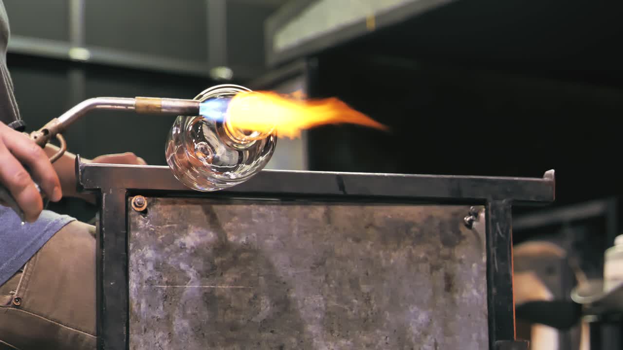 Artista del vetro che modella un vaso rotante con la fiamma