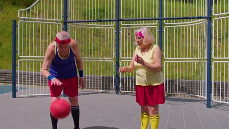 senior woman coach teaching grandfather with basketball dribbling exercise with ball on playground