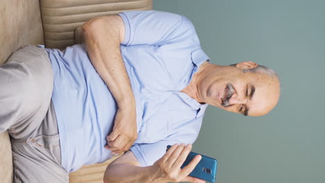 Vertical-video-of-Old-man-using-phone-with-happy-expression.-The-old-man-is-enjoying-it.