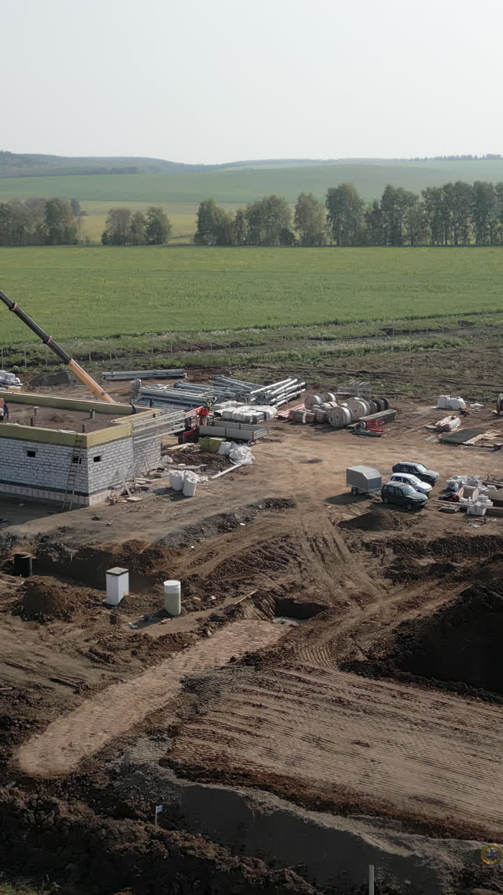 Construction Site with Building Under Development and Crane in Rural Landscape