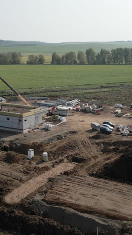 construction site with building under development and crane in rural landscape