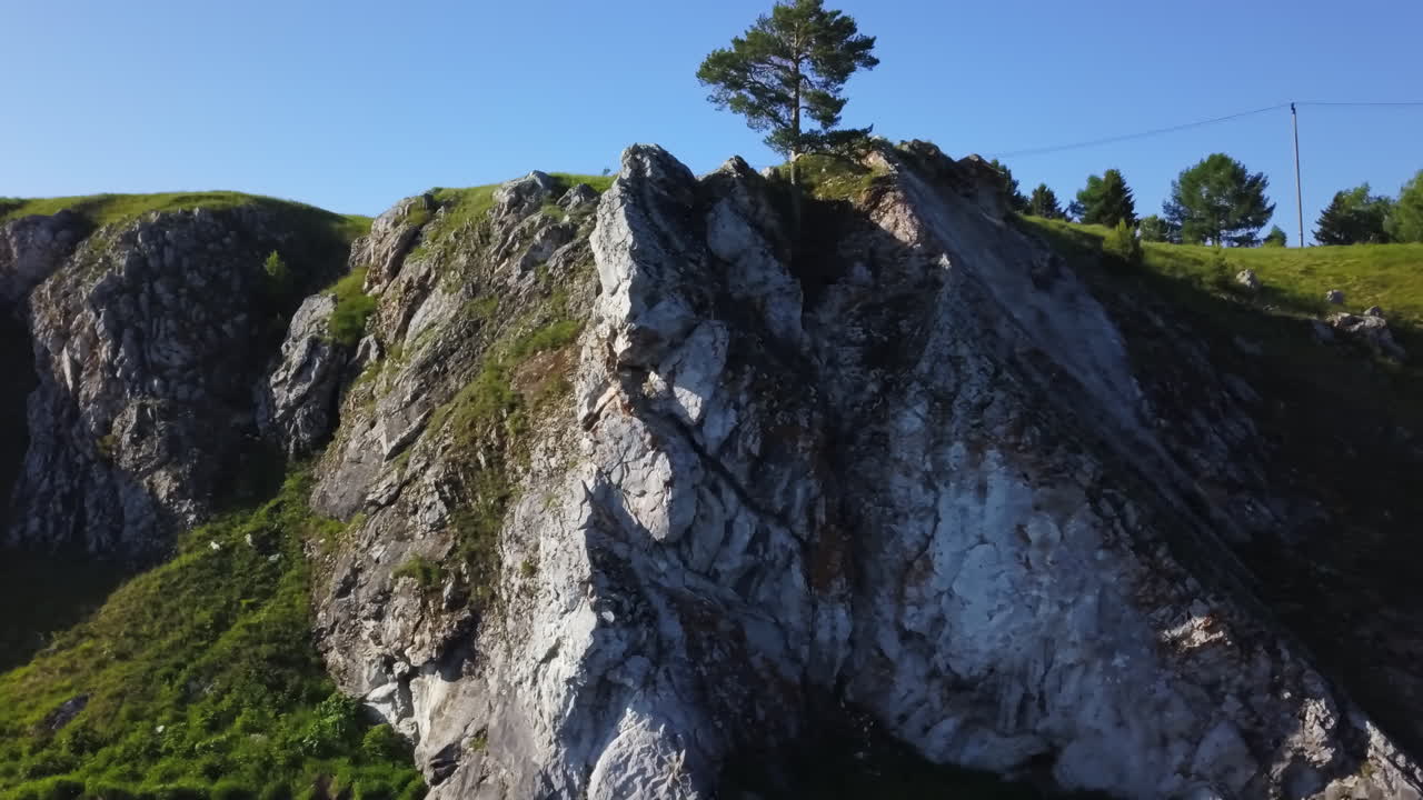 Klippefyldt bjerglandskab med klippevæg og træer