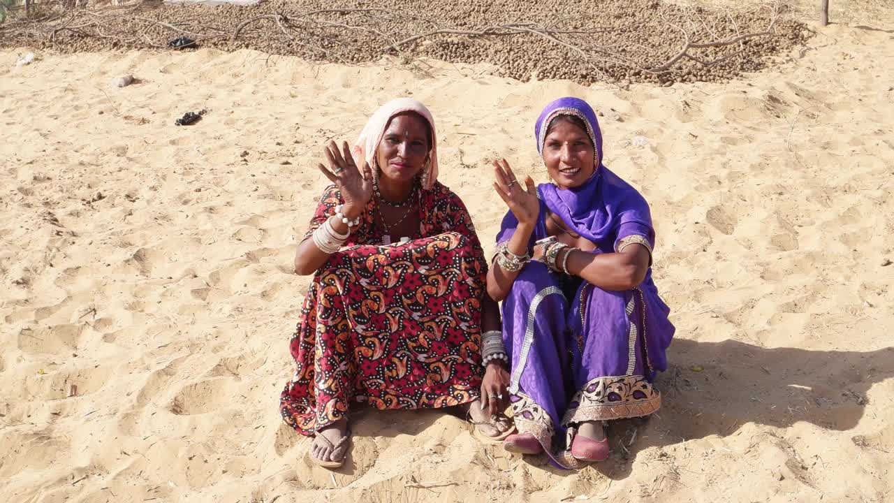 dos mujeres rajasthani sonriendo y agitando las manos adiós y adiós