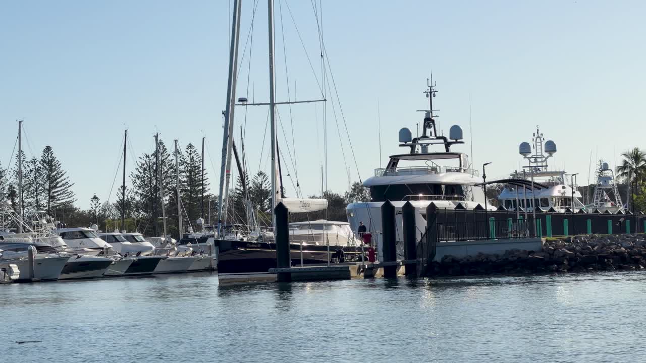 Ampia inquadratura statica di superyacht e barche a vela di lusso ormeggiati in un tranquillo porto australiano