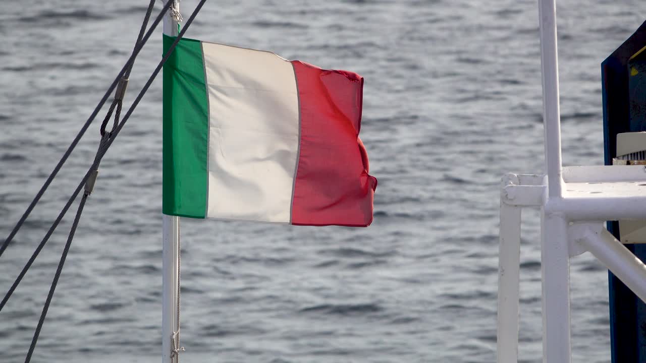 Bandiera italiana sventola in una violenta tempesta su una piccola barca sulla costa della Sardegna