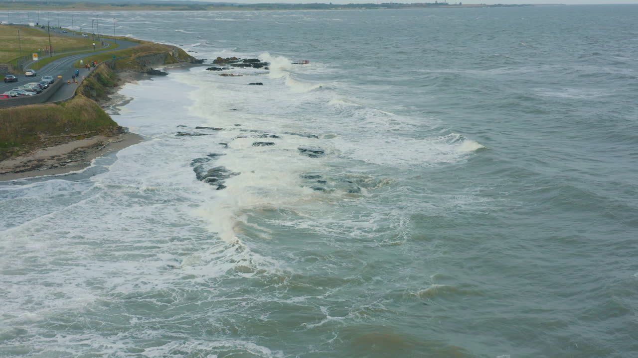 vista aérea de las olas rompiendo contra las rocas a lo largo de la costa durante una tormenta