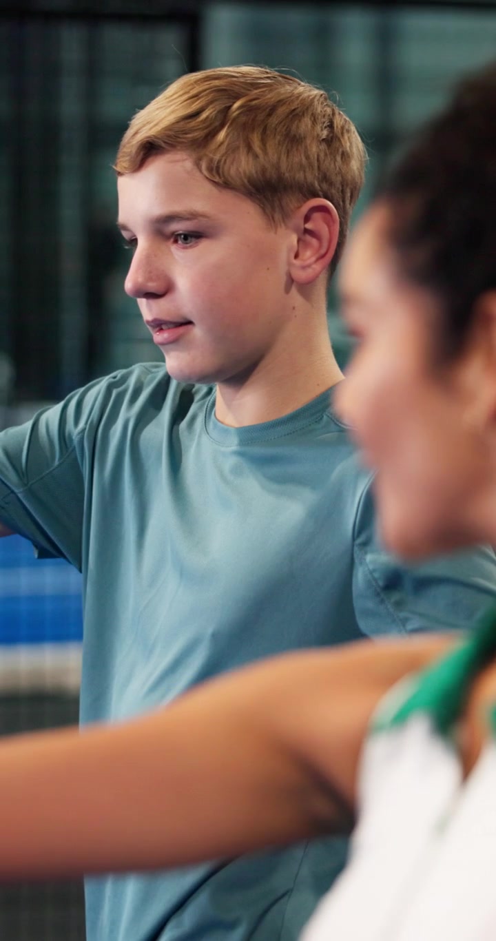 Tennis Coach Instructing Young Boy on Court