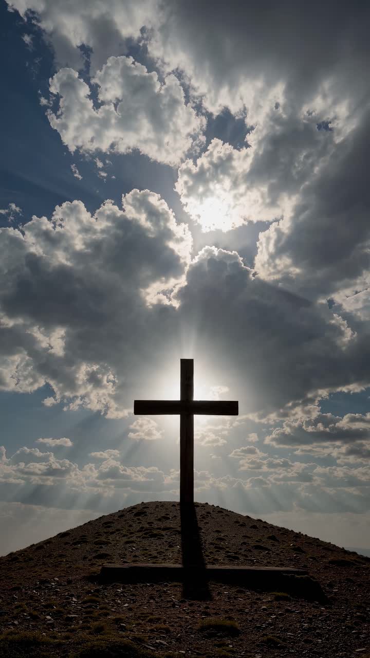 Dramatic low-angle shot of a cross silhouetted against a cloudy sky, capturing a spiritual