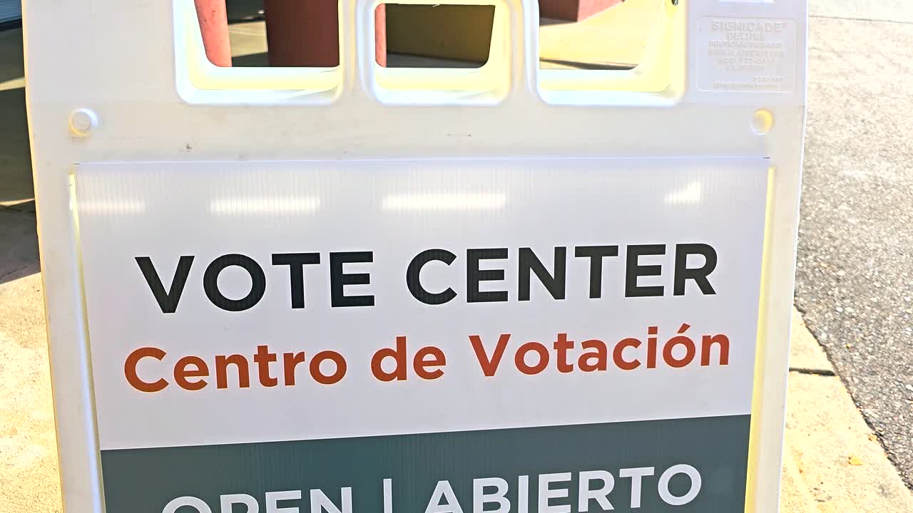 A bilingual sign “Vote Center, Centro de Votación – Open, Abierto” with Spanish translation is shown outdoors, representing inclusivity, registration services, mail ballot support and in-person voting