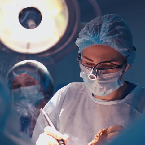 surgery in the operating room. portrait of a woman surgeon working with medical equipment. face of professional doctor in medical mask.