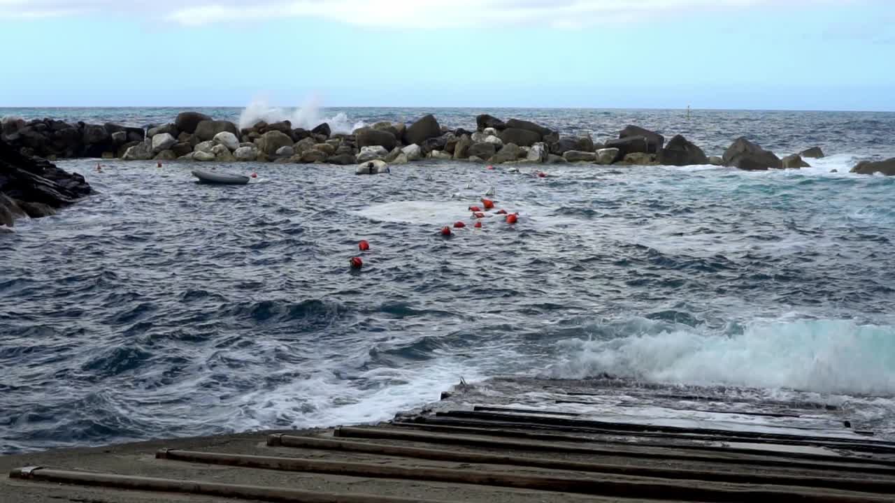Cinque Terre, Liguria, Włochy – fale wpływają do małego portu oznaczonego czerwonymi bojami i chronionego przez skalny falochron – szeroki kąt