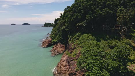 aerial tracking shot of tropical coastline and ocean relieving three tropical islands in thailand