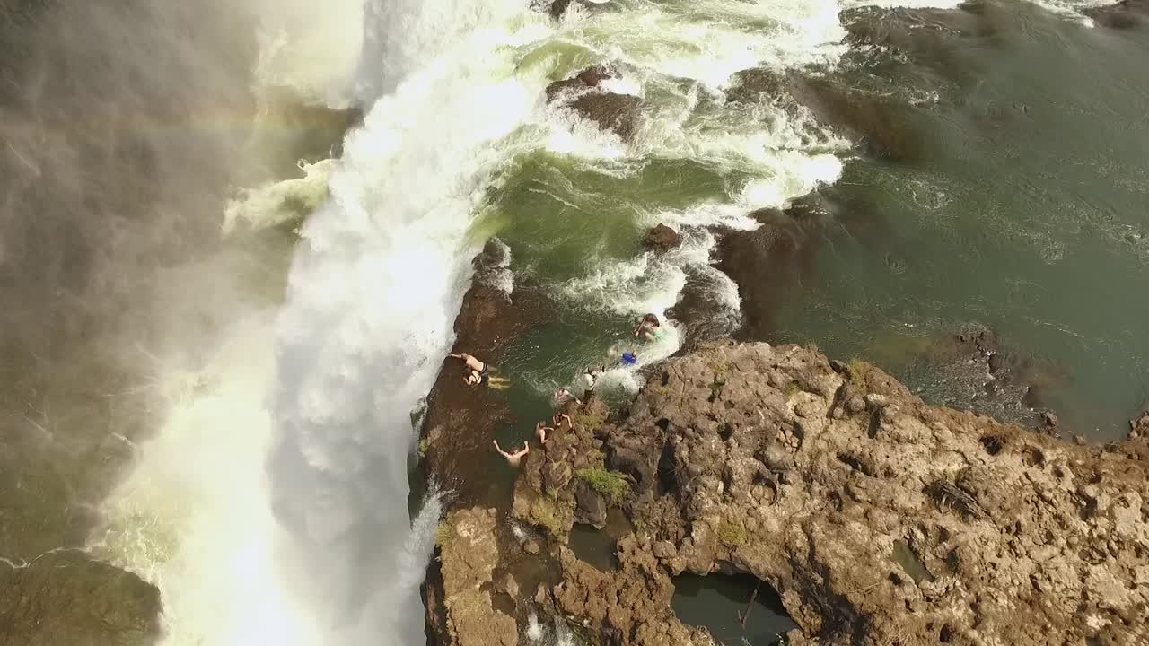 una vista aérea muestra a los turistas nadando sobre las cataratas victoria en la piscina del diablo en zambia