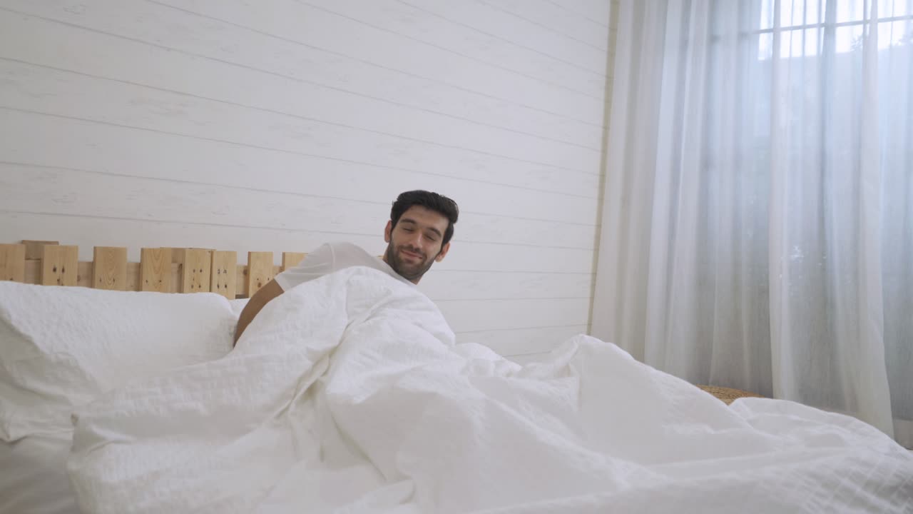 joven somnoliento de oriente medio despertando. personas acostadas y durmiendo en la cama en el dormitorio temprano en la mañana en casa. estilo de vida