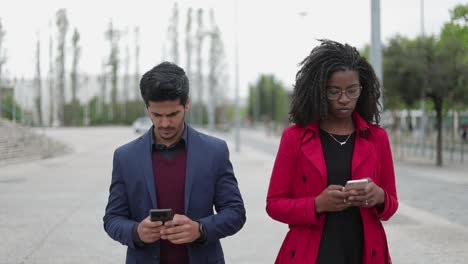 Mujer-Afroamericana-Y-Hombre-De-Raza-Mixta-Caminando,-Enviando-Mensajes-De-Texto-Por-Teléfono