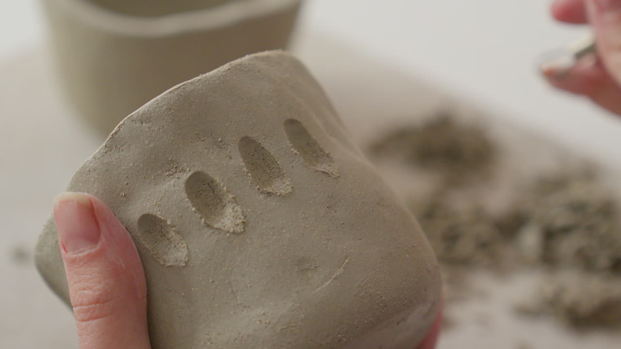 Masterfully etching intricate designs into soft clay with a specialized tool, showcasing artisan's delicate touch