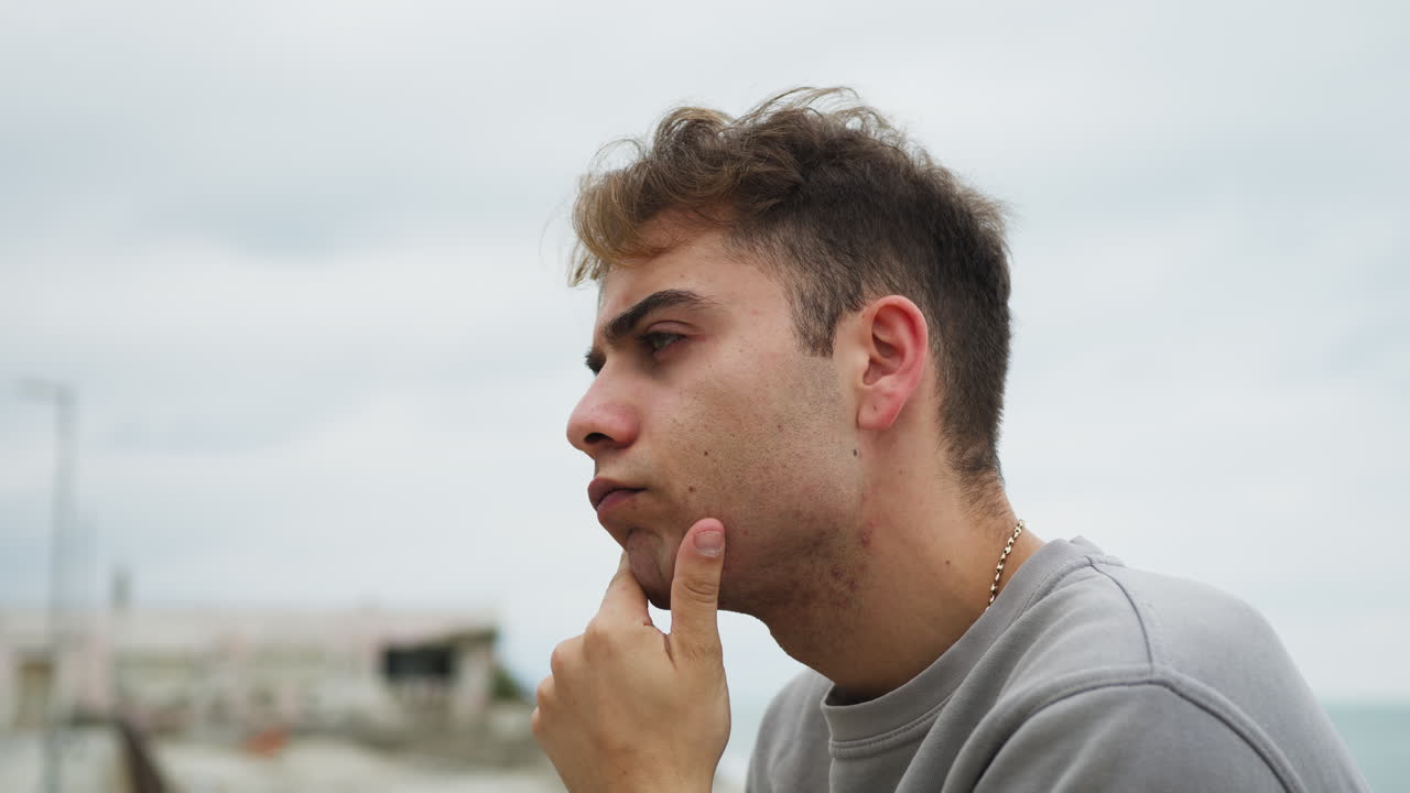 niño con expresión pensativa en su cara mira hacia el horizonte en la playa