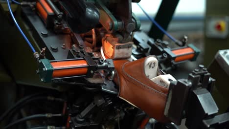a craftsman handmade a shoe by a machine, close up shot, insert shot